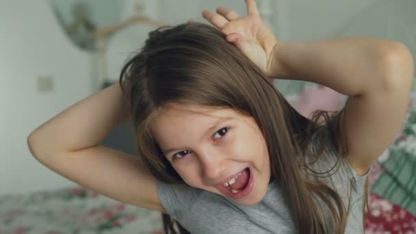 Close-up de bonito menina engraçada sorrindo rosto sorridente e olhando para a câmera enquanto sentado no quarto em casa — Vídeo de Stock