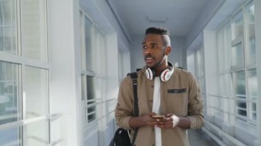 Geniş cam gibi koridor ayakta, onları sallayarak ve tebessüm ederek geçen fark beyaz ve Asyalı kızlar arama gidiş pozitif Afro-Amerikan öğrenci