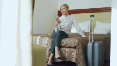 Mutlu işkadını yatak otel odasında oturup..... smrtphone kamera kullanarak online video sohbet yoluyla ailesiyle konuşuyor. Seyahat, iş ve insan kavramı