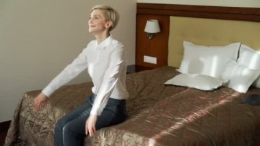 Düşen ve otel odasında rahat yatakta yatan bir işkadını gülümseyerek. Seyahat, iş ve insan kavramı