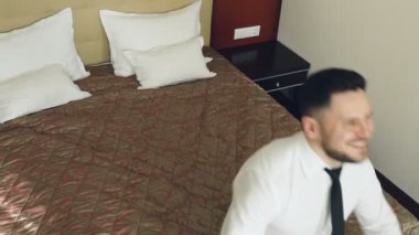 Üstten Görünüm ağır çekim yatak otel odası ve yalan üzerinde atlama mutlu iş adamı gülümseyen rahat. İş, seyahat ve insanlar kavramı