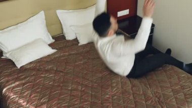 Üstten Görünüm ağır çekim yatak otel odası ve yalan üzerinde atlama mutlu iş adamı gülümseyen rahat. İş, seyahat ve insanlar kavramı