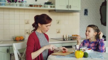 Sebze yemek ve neşeli kızı evde mutfakta konuşmak mutlu genç anne. Aile, aşçı ve insanlar kavramı