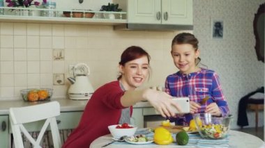 Anne yapma selfie fotoğraf genç sevimli kızı yemek kahvaltı evde birlikte mutfakta gülümseyerek. Aile, aşçı ve insanlar kavramı