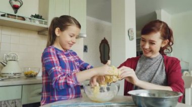 Mutlu anne ve birlikte yemek ve eğlenmek güzel kızı. Kızı elinden yapışkan hamur kapalı alarak ve birlikte gülüyor anne. Aile, gıda, ev ve insan kavramı