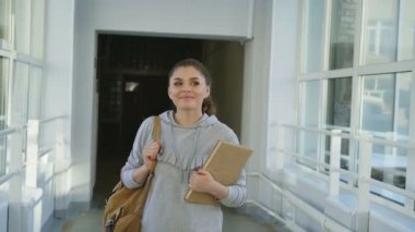 Genç çekici güzel kız yukarıya bakıp uzakta sersem onlara el sallayarak ve devam ediyoruz arkadaşları tarafından geçen geniş ferah Üniversitesi koridordan gidiyor