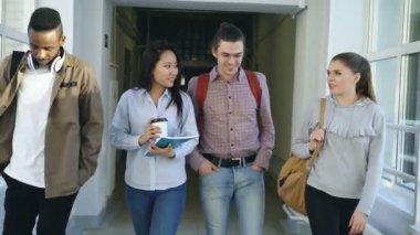 Mutli-etnik grup erkek ve dişi öğrenci çalışma gülümseyen ve olumlu Birbirinizle konuşmak gülüyor tartışırken Üniversitesi büyük koridor yürüme