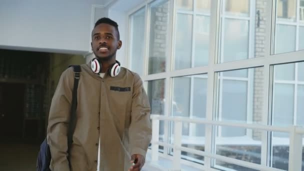 Boldog afrikai amerikai férfi hallgató Egyetem folyosó hirtelen forrás váll, csípő szemtelen fickó sétál, és a mozgás mérgesen. Faji megkülönböztetés, a fiatalok és az iskolában koncepció — Stock videók