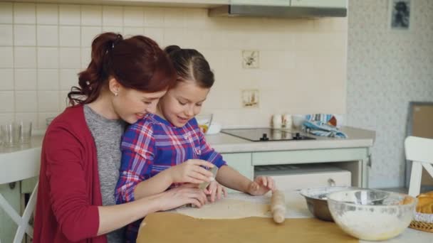 微笑的母亲和可爱的女儿做圣诞饼干一起坐在厨房餐桌在家里。家庭, 食物和人概念 — 图库视频影像