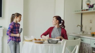 Pişirme sırasında genç anne çalışırken hamur ve çevresinde yürüyüş ve ile şarkı komik kızı mutfakta hafta sonu dans tarak. Aile, gıda, ev ve insan kavramı