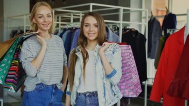 Güzel genç kadın portresi ile Bayan giyim butik ellerinde kağıt torbalarda bekliyoruz. Moda Giyim, çanta, Ayakkabı ve baloons arka planda.