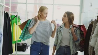 İki kadın arkadaş geniş butik yavaş yavaş yürüyor. Sohbet ve güzel giysiler ve ayakkabı askılar ve raflar bakarak çok sayıda kağıt çanta, burada tutuyorlar.