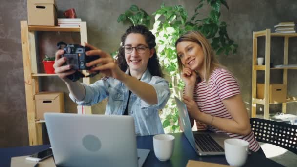 Kreatív tervezők jelentő selfie együtt ül modern irodában. Ezek fényképezőgép használata, nevetve és szocializáló. Ifjúsági életmód fogalma. — Stock videók