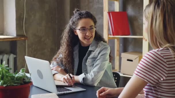 Fiatal kis üzlet tulajdonosa beszél, hogy ő ügyfél, modern irodában. Nők ül íróasztal, beszélgetni, és barátságos módon együtt nevetünk. — Stock videók