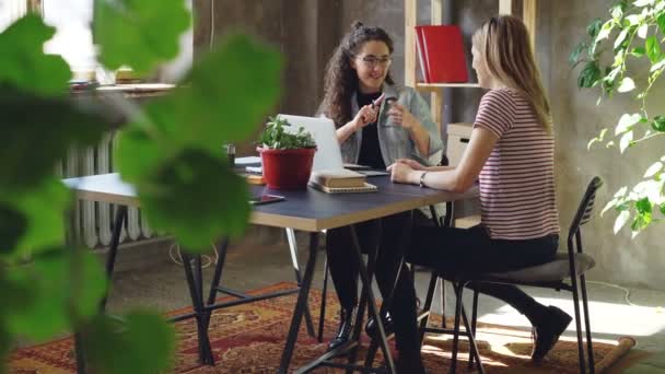 年轻的企业家是 duscussing 的广告策略, 而坐在现代办公室的桌子。女人在说话和手势, 其中一个正在做笔记。. — 图库视频影像