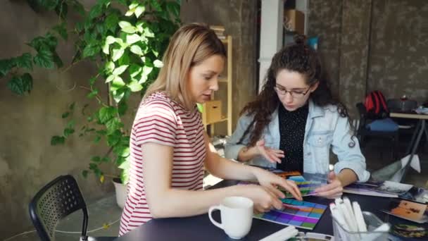 Kobiece projektanci pracują z palety kolorów, aby określić kolory na zdjęciu. Oni świętują sukces z high five. Dzień pracy w koncepcji firmy projektowej. — Wideo stockowe