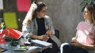 Başlangıç girişimciler iş birlikte modern ofiste otururken görüşüyorlar. İşbirliği, cam ön planda parlak renkli çıkartmaları ile dostane bir atmosferde.