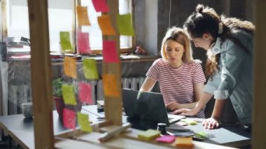 Öğrenciler loft daire içinde sosyalleşme. Sarışın bilgisayar kullanıyor ve kablosuz kulaklık ile onun arkadaşı onunla neşeyle sohbet.