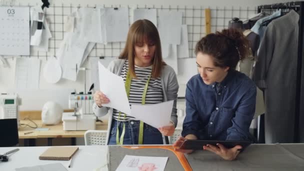 Los diseñadores de vestuario clreativo están mirando dibujos y comparándolos con imágenes en la tableta. Inicio exitoso en concepto de industria de la moda . — Vídeo de stock