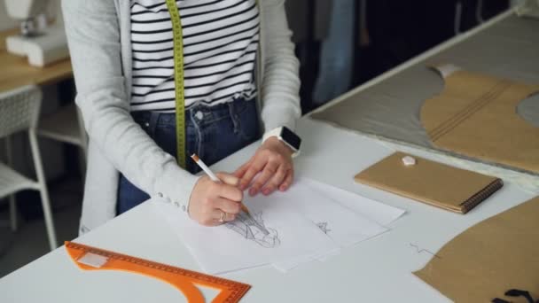 Tilt-up çekim yaratıcı giyim Tasarımcısı kroki kadın giysi kağıt parçası üzerine kalemle çizim yoğunlaşmıştır. Moda giysiler kavram oluşturma. — Stok video