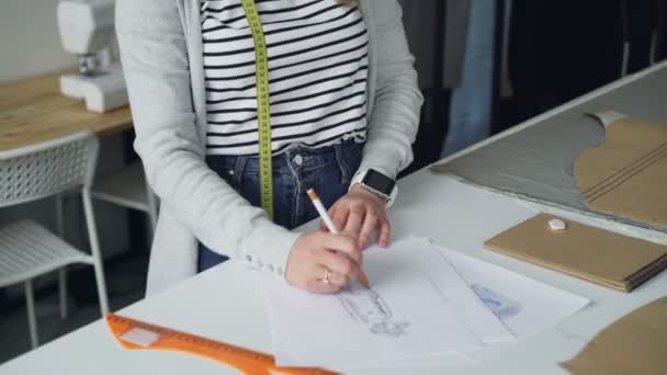 Inclinez-vous de l'artiste féminine et créatrice de vêtements dessine vêtements pour femmes pour le futur défilé de mode. Plan incliné de croquis sur le bureau du studio, les mains des filles puis le corps et l'atelier . — Video