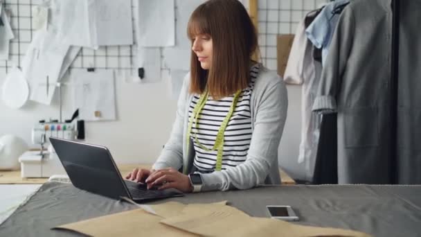 Ženské oblečení design podnikatel používá notebook s její klienty komunikovat a prodávat vyrábí oděvy. Moderní e-commerce v malé obchodní koncept. — Stock video