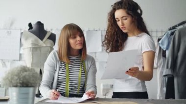 Profesyonel kadın moda tasarımcıları kroki seyir ve gelecekteki giysiler ayrıntılarını tartışıyor. Verimli işbirliği ve oluşturma yeni koleksiyon kavramı.