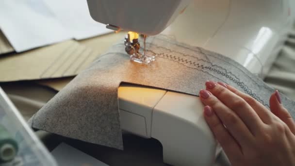 Close-up shot van de naaimachine, stof en gemanicuurde vrouwelijke hand. Kleding productie proces concept. Lichte, zachte kleuren — Stockvideo