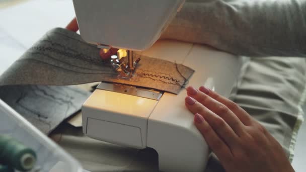 Крупним планом вид сучасної електричної швейної машини працює швейний шматок тканини. Дівчата доглянуті рука і барвисті швейні нитки видно . — стокове відео