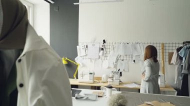 Çekici kadın giyim Tasarımcısı duvarda asılı sonra yeni çizimler seçtiğiniz giysi skeçler arıyor. Manken elbiseler moda giysiler içinde ön planda olduğunu.