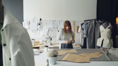 Çekici terzi giyim kağıt şablonları ölçü-teyp ile stüdyo masanın üzerinde yatan ölçmek. Sakin ve terziler Dükkanı, eser üzerine konsantre kadındır.