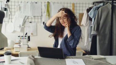 Başarılı terzi girişimcisi cep telefonuyla konuşuyor ve dizüstü bilgisayar kullanıyor. Kadın tekstil tedarikçisinden kumaş sipariş etmekle meşgul. Kıyafet tasarımı başlangıç konsepti.