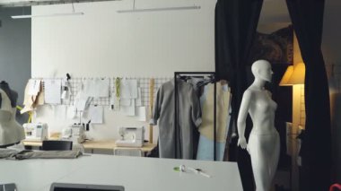 Işık giyim tasarım stüdyosu büyük terziler Resepsiyon, mankenler, çok sayıda skeçler duvar, dikiş makineleri ve bitmedi giysiler raylar üzerinde pinned ile kadeh kaydırmak.