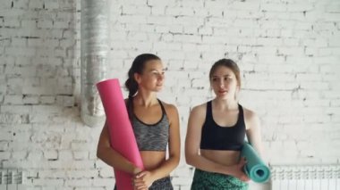 Yoga Studio renkli paspaslar ile yürüme ve konuşma trendy spor giyim iki genç kadın Dolly vurdu. Kızlar başarılı çalışmadan sonra duyguları paylaşıyoruz.
