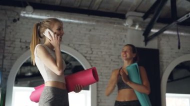 Arkadaşı ona, sarılma ve başarılı uygulama ile tebrik gelirken çekici sarışın üstünde hareket eden telefon içinde jimnastik salonu konuşuyor. Mutlu kadın spor merkezi kavramı.