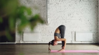 Çekici kız ileri vurgun yapıyor plank, kişisel yoga eğitim sırasında güzel Studio'da split bacak. Kolayca zor pozisyonlar yönetiyor. Esneklik güç kavramı.