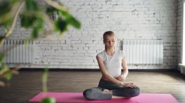 Çekici ince sarışın tarafına bükme sonra lotus pozisyonda elleri dizlerinin üzerinde rahatlatıcı büküm pozlar yaparken yoga pratiği yapıyor. Bireysel uygulama kavramı.