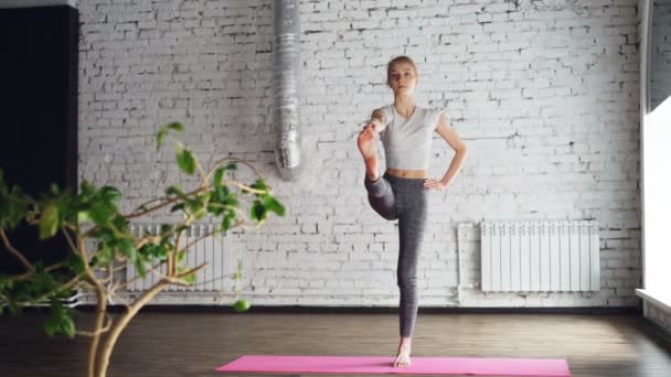 Começando estudante de ioga feminino está fazendo a sequência de exercícios de equilíbrio na aula de ioga one-to-one. Às vezes, ela é estranha, mas faz bons progressos. Aprendendo ioga conceito . — Vídeo de Stock