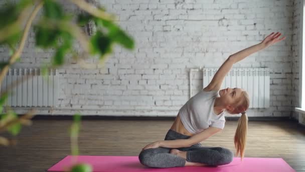 Attrayant fille pratique yoga flexion de côté avec le bras vers le haut puis se détendre dans la pose de lotus facile sur la session individuelle dans le centre de bien-être. Fexibilité tranquillité concept de méditation . — Video