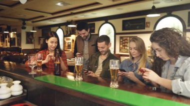 Gençler akıllı telefonlar, bar counter birlikte otururken kontrol ediyor. Birbirimizi bahsediyoruz ekranlar, gösteriyorlar. Modern teknolojileri iletişim kavramı.