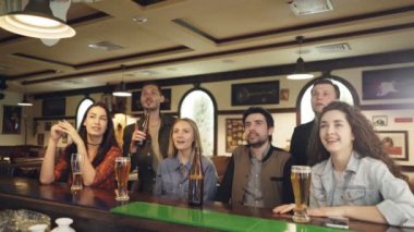 Arkadaşlar futbol taraftarları spor bar önemli maçı izlerken ve sonuçta eğleniyor tezahürat yapıyor. Bardakları tokuşturup ve bira içmek.