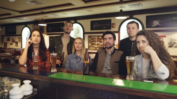 Eine Gruppe von Freunden schaut sich in der Sportsbar bei Bier ein Eishockeyspiel im Fernsehen an. Sie sind ängstlich und nervös, weil ihre Lieblingsmannschaft das Spiel verliert. Emotionales Fankonzept. — Stockvideo