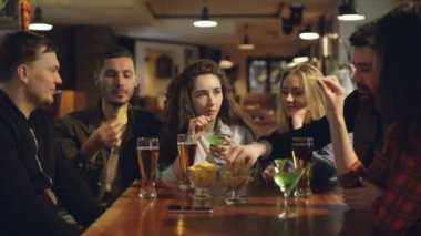 Arkadaş grubu içme, abur cubur yemek ve masada otururken konuşurken çubuk. Gençler kendilerini zevk ve pub kavramında iletişim.