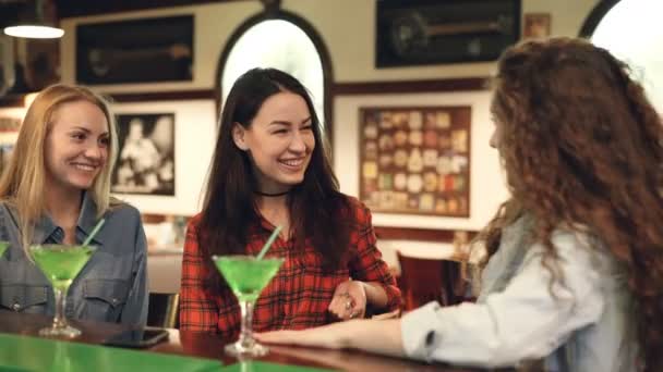Cheerful female friends are socializing in fancy bar. Attractive women are chatting, laughing and touching cocktail glasses. Girls having fun concept. — Stock Video