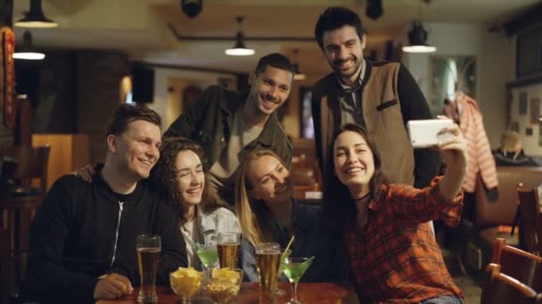 Jeune femme brune prend selfie avec ses amis dans le café. Belles personnes s'amusent ensemble, posant et riant . — Video
