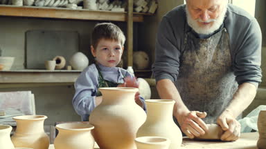 Deneyimli erkek potter karıştırma ve sevimli genç torunu atölyede ona yardım ediyor iken kil yoğurma. Çanak çömlek, Aile geleneği ve çocukluk kavramı.