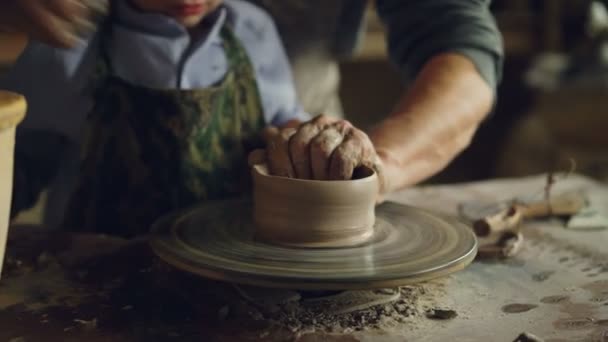 Close-up shot van vier handen opa en kleinzoon molding keramische pot op draaiende wiel samen te gooien. Aardewerk, hobby en handwerk concept. — Stockvideo