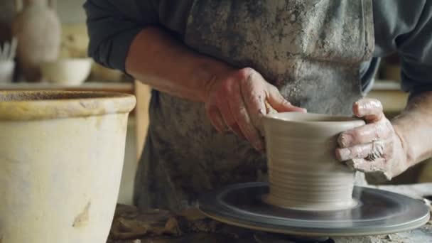 Detailní záběr rozpracovaných keramická váza předení na potterss kolo a ruce lisování jíl s profesionálními nástroji. Vytvoření okrovozelená a tradiční keramiky concept. — Stock video