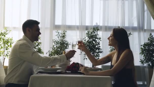 Les jeunes couples heureux sont cliquetis verres et boire du champagne sur la date romantique dans le restaurant cher. Romance, amour et concept gastronomique . — Video