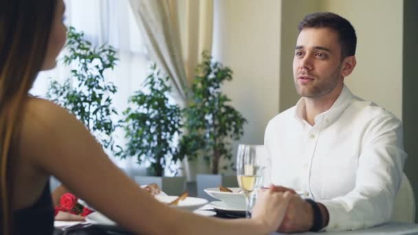 Šťastné milující muž v bílé košili se navrhuje překvapeni krásnou přítelkyni, pak dává její zásnubní prsten během romantické rande v restauraci. — Stock video